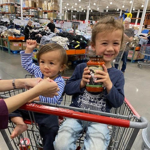 Picture of children in shopping cart holding Dellamore sauce